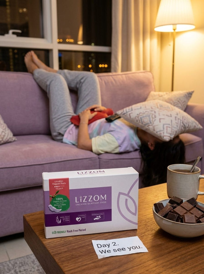 Woman lying upside down on a sofa with a hot-water bottle, LiZZOM box on the table